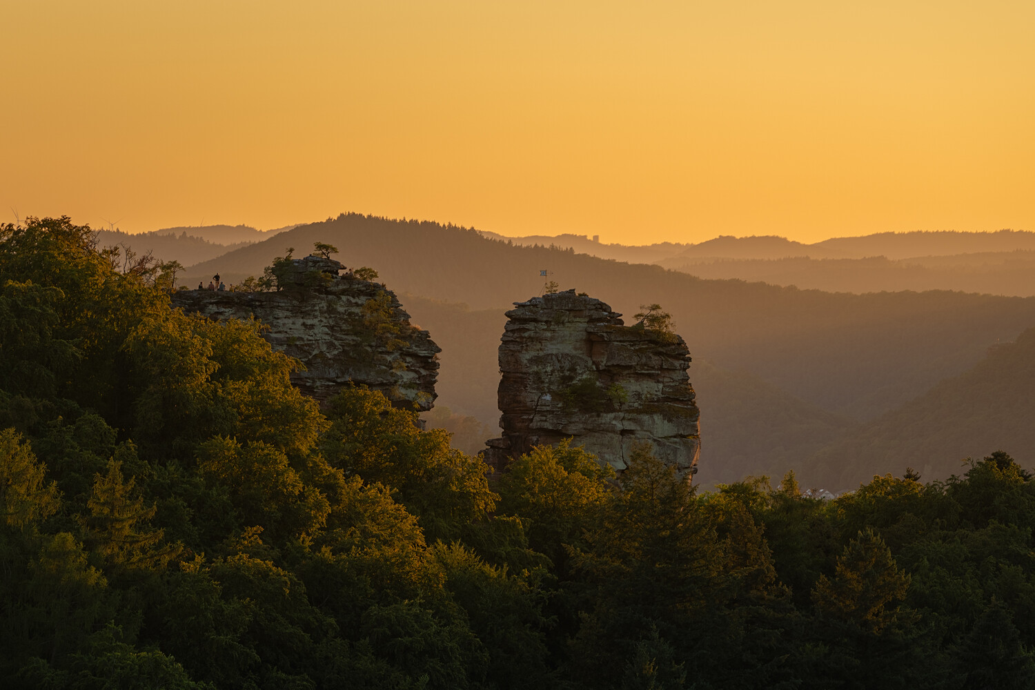 Dramatic rock formations rising from forested landscape at golden hour