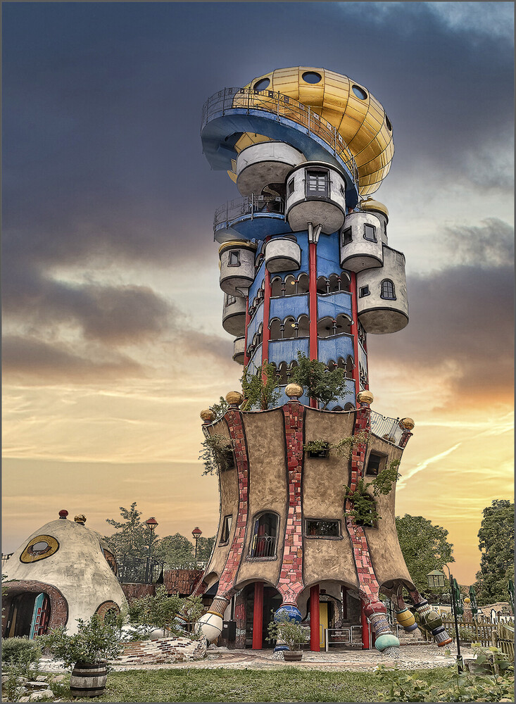Fantastical stacked tower structure with colorful cylindrical sections and golden sphere top against dramatic sunset sky