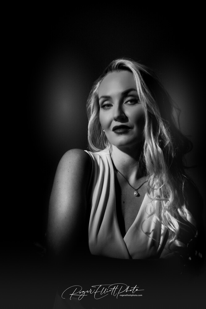 Woman with long blonde hair in dramatic black and white studio portrait lighting