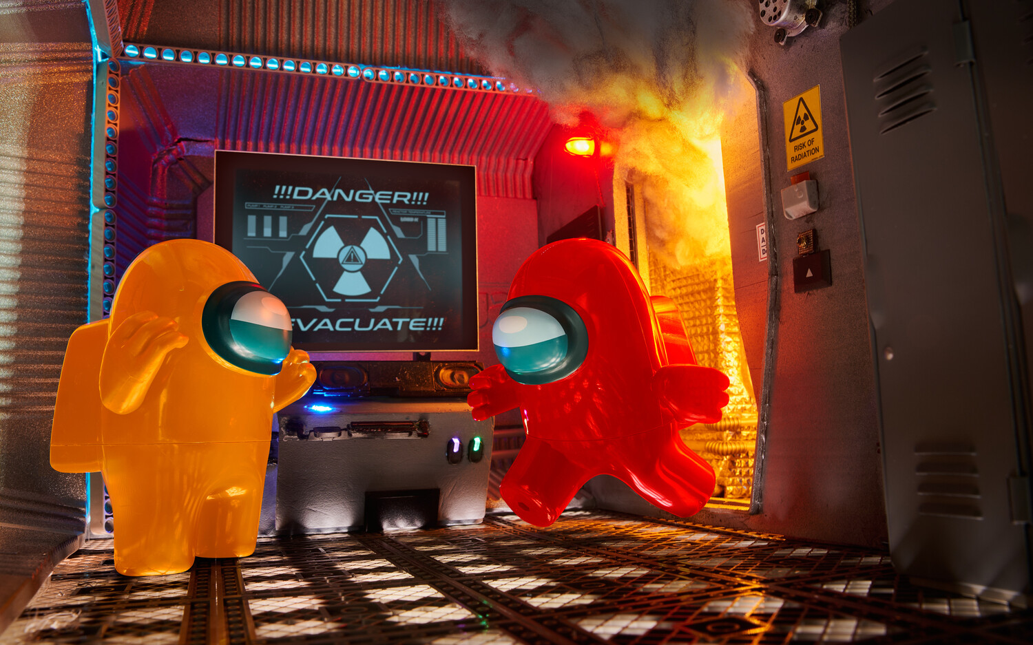 Two inflatable alien figures in neon orange and red positioned in front of a glowing sci-fi warning display