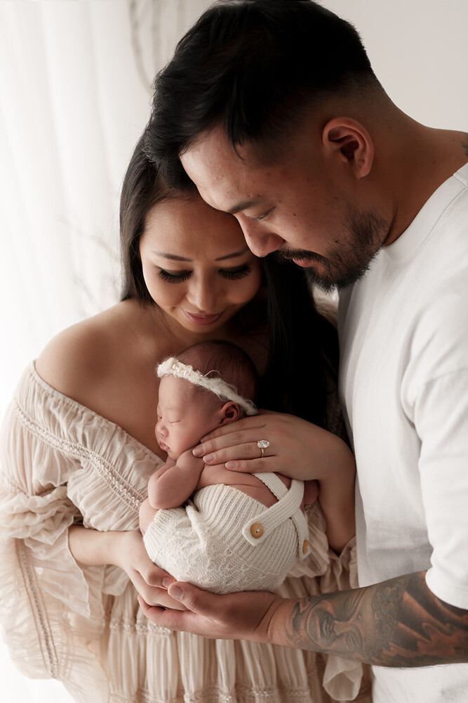 Parents holding newborn infant in soft natural light