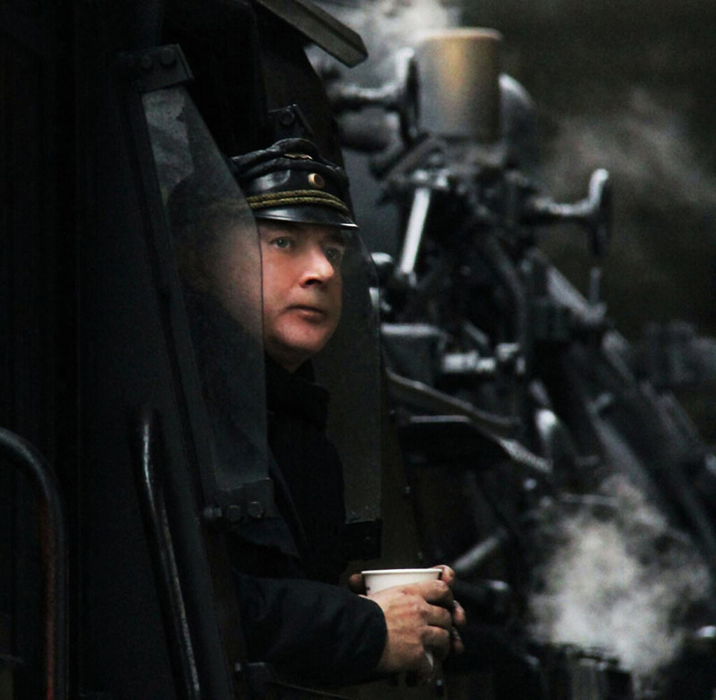 Person in dark clothing and cap holding smoking pipes, shot in dramatic low-key lighting