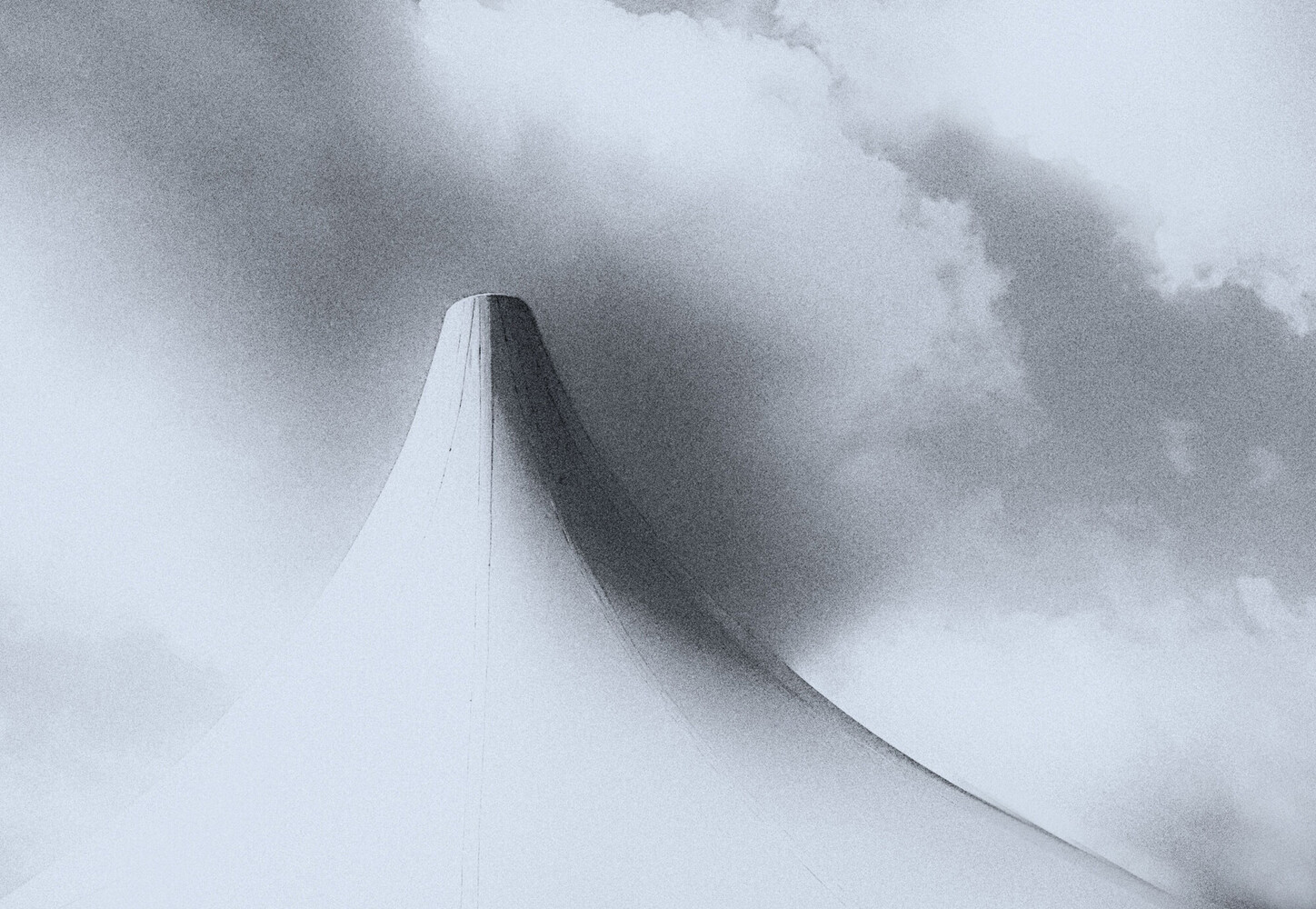 Minimalist white structure emerging from dense fog and clouds