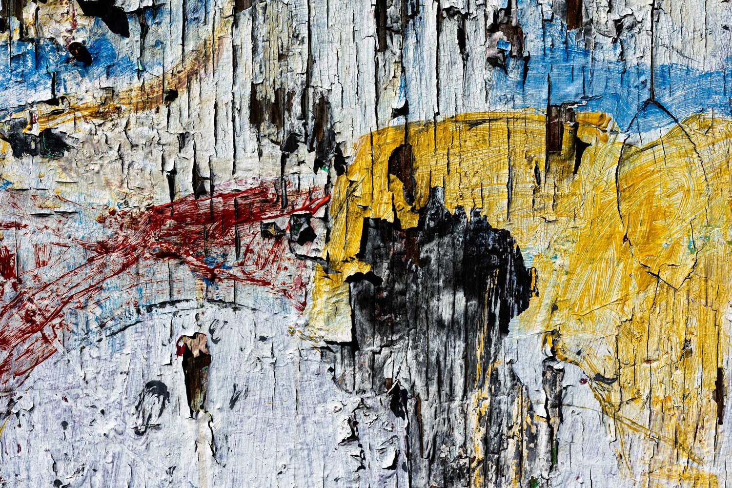 Close-up of a weathered surface with peeling white, yellow, blue, and red paint layers forming an abstract texture