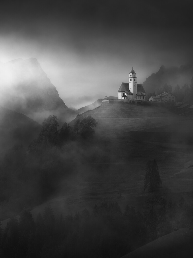 Church perched on hilltop surrounded by dense fog and forested mountains