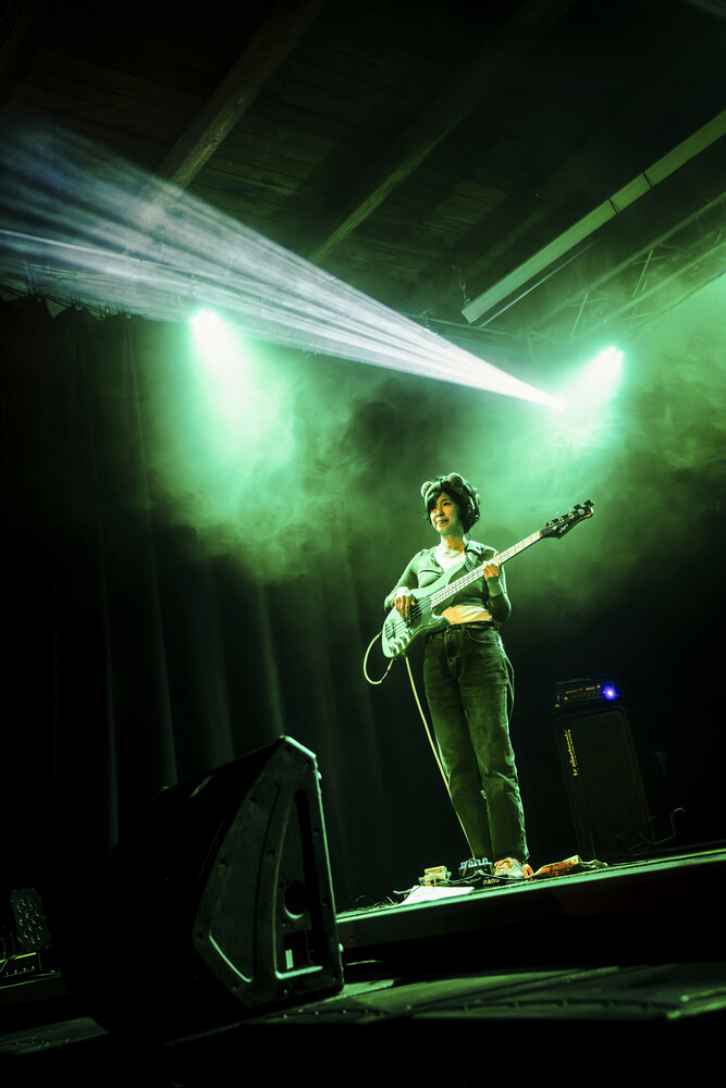 Guitarist performing on stage with dramatic green atmospheric lighting and beam effects