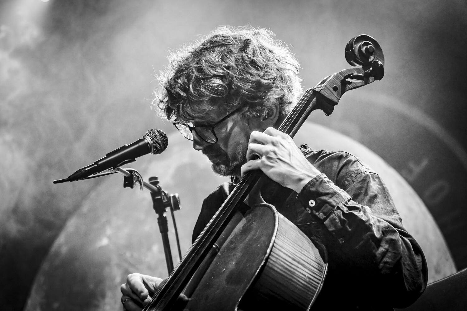 Cellist performing at a microphone during a live concert performance