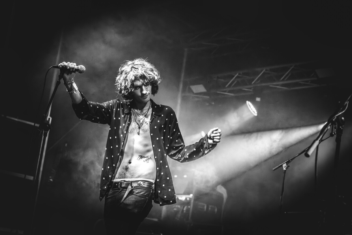 Performer on stage wearing a studded jacket, singing into a microphone with dramatic stage lighting