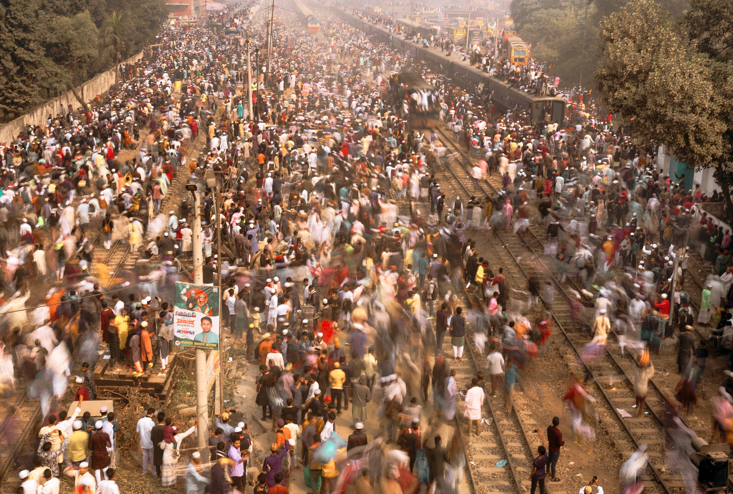 Massive crowd of thousands filling a wide street and railway tracks stretching into the distance