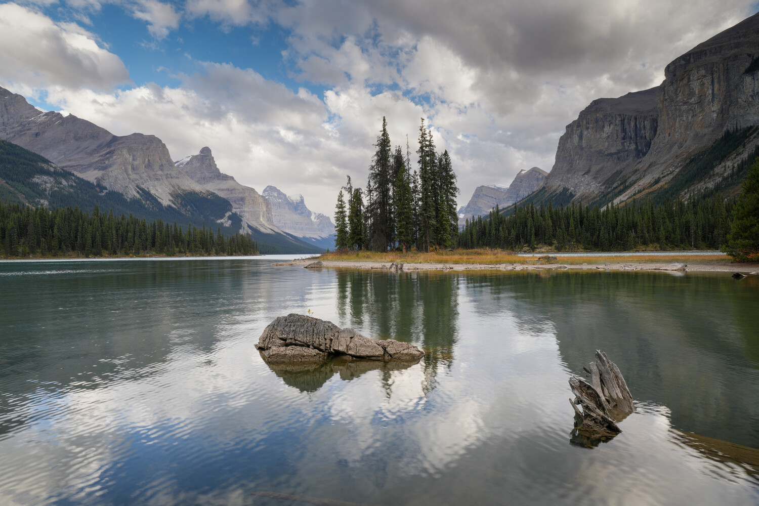 Mountain lake with forested island and rocky outcroppings reflecting in calm turquoise water