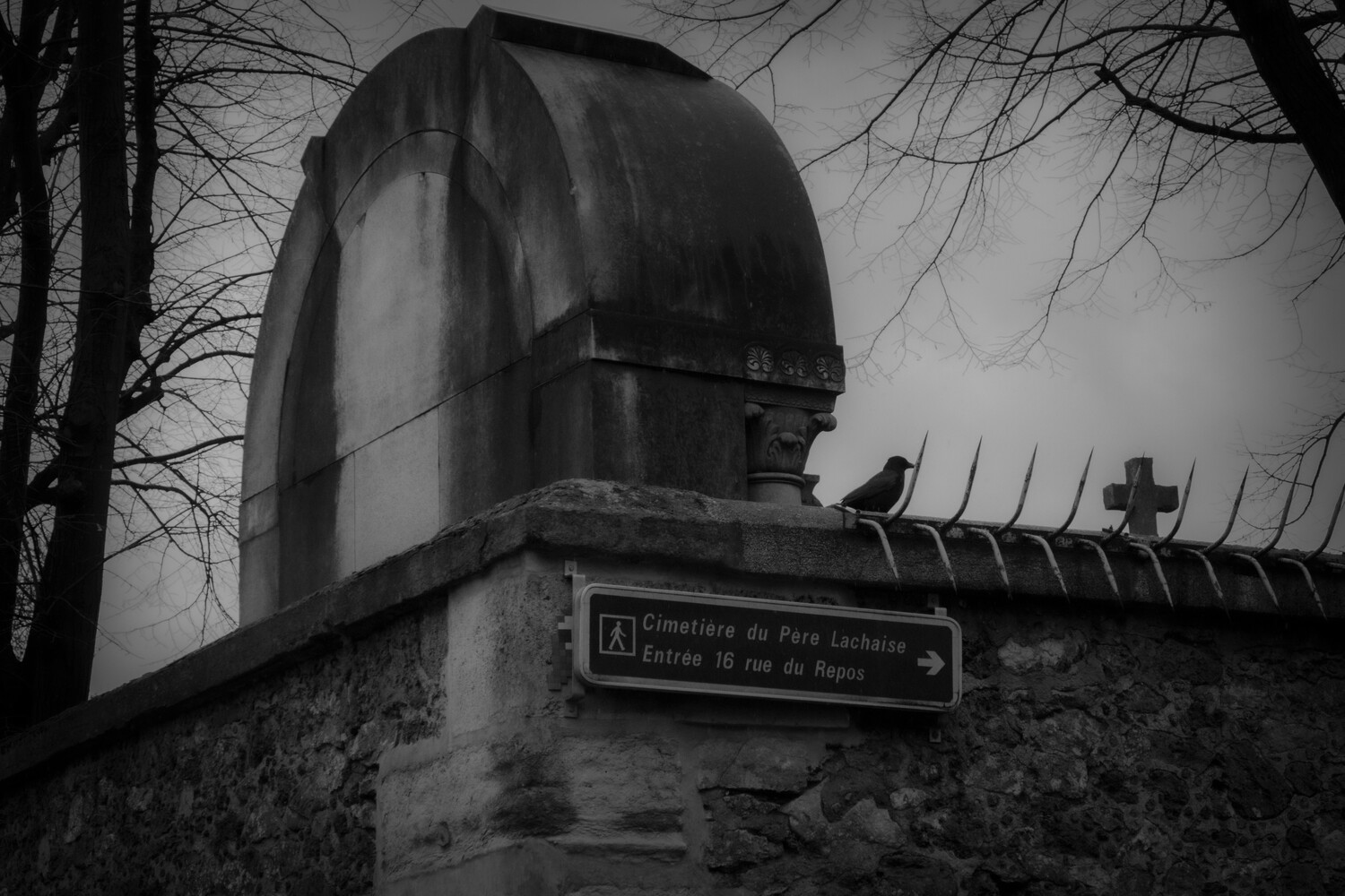 Domed observatory structure with crosses atop fence, bare branches visible against overcast sky