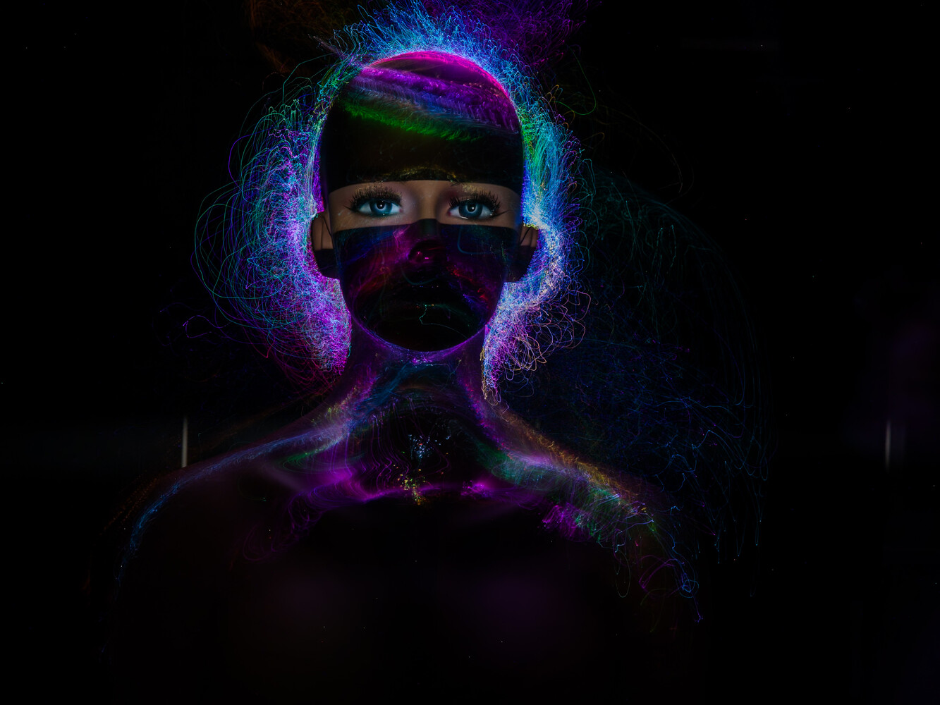Portrait of a person with vibrant neon body paint and glowing light effects against a dark background