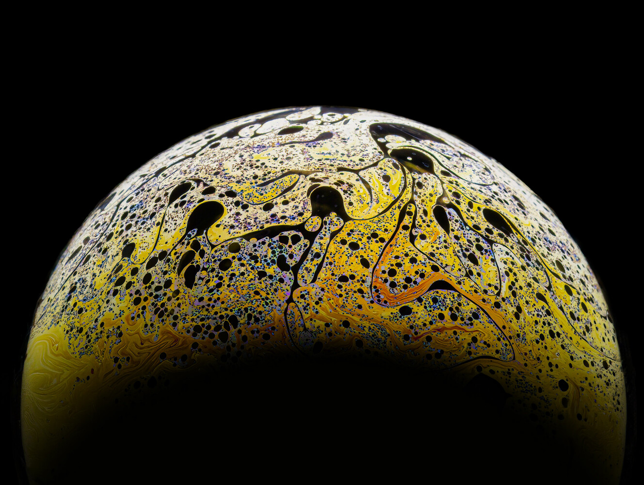 Yellow and white sphere with black spatter and organic markings against dark background