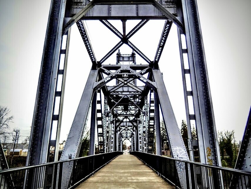 Symmetrical view down the center of an industrial steel bridge with X-braced trusses