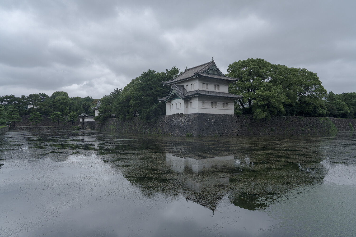 Traditional Japanese castle tower reflected in still water surrounded by trees