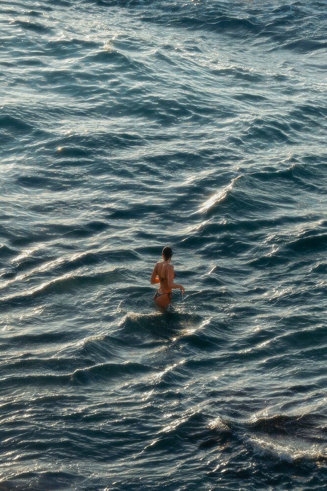 Shirtless swimmer in ocean water during golden hour