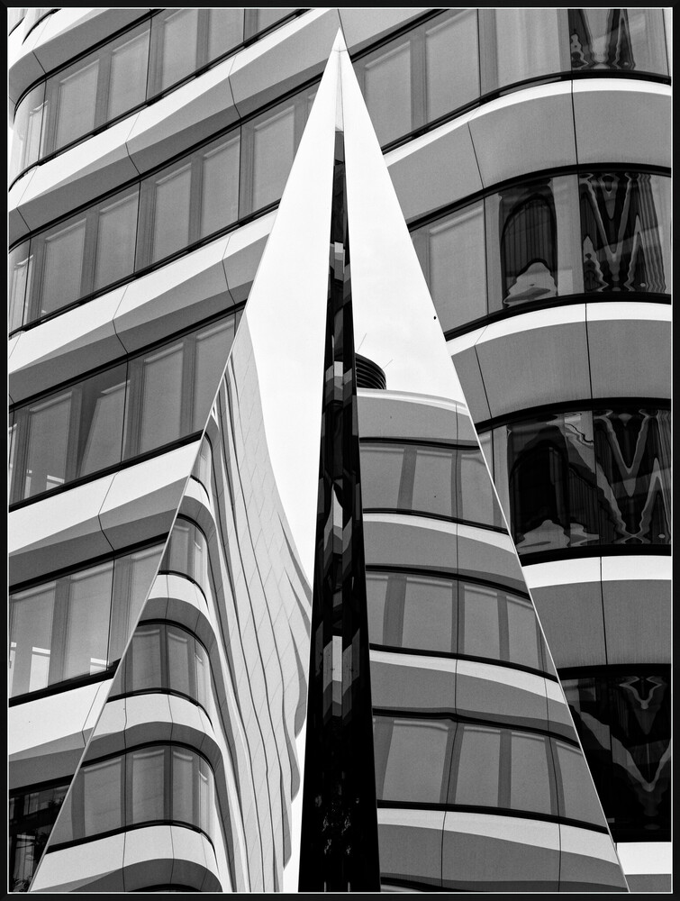 Black and white architectural photograph of curved building facades with dramatic vertical lines and geometric patterns