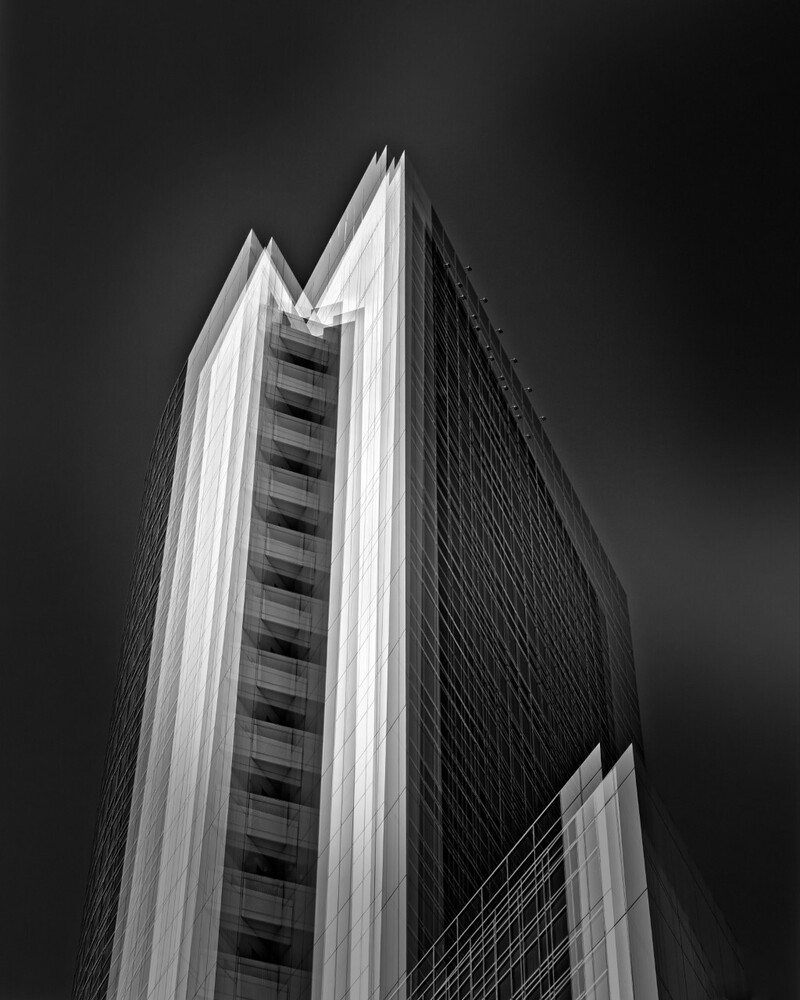 Modernist skyscraper photographed from below in black and white, showing geometric vertical lines and angular forms
