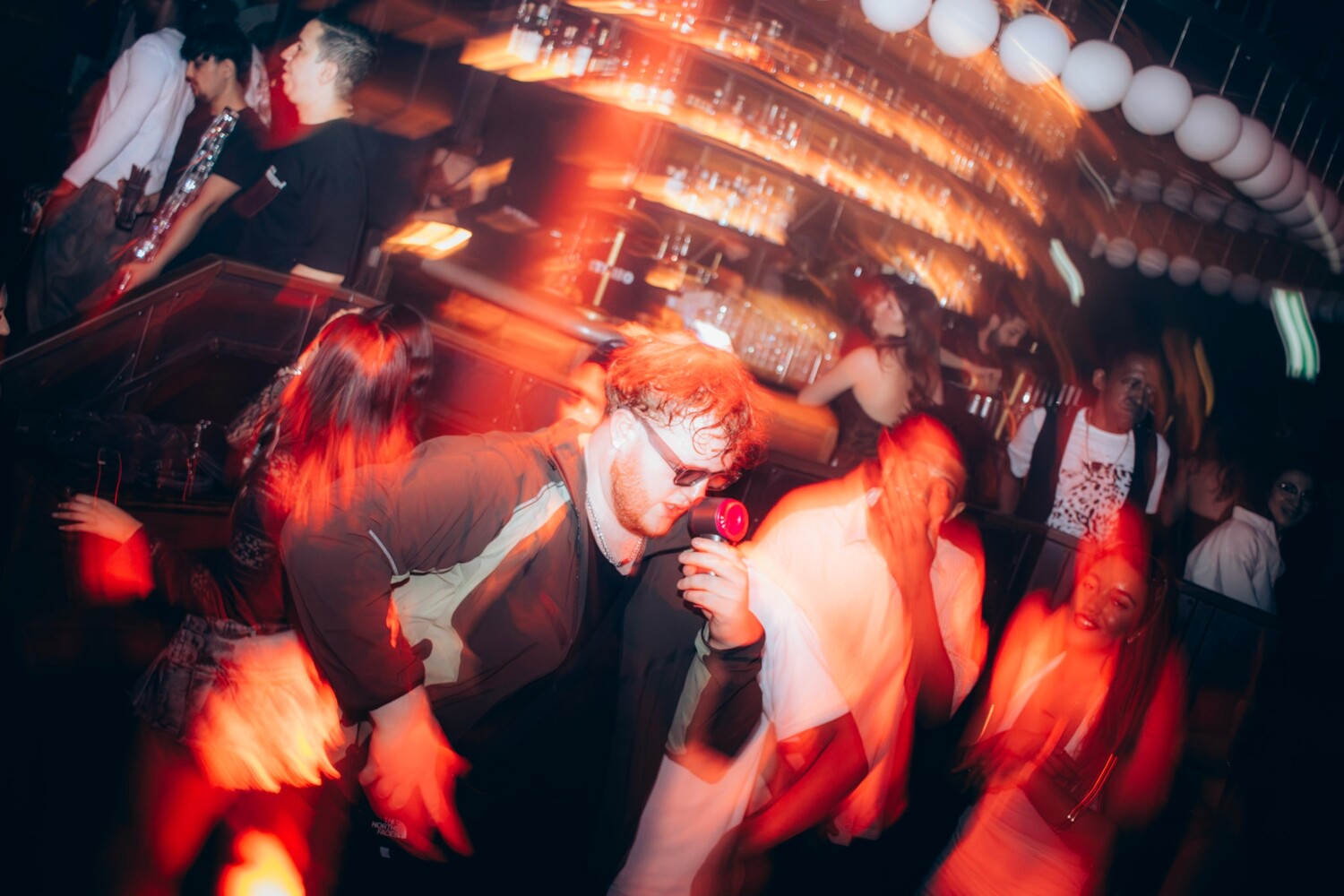 Crowded nightclub dance floor illuminated by intense red and orange lighting