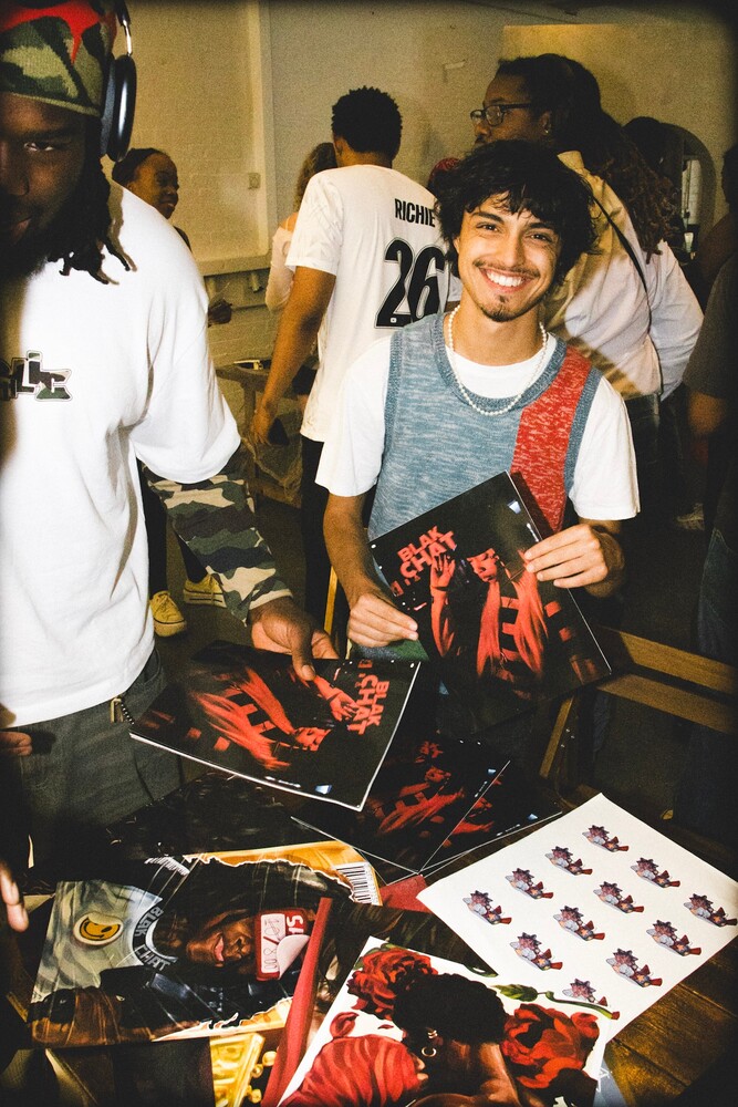 Young person in casual wear examining merchandise at a table during a community event
