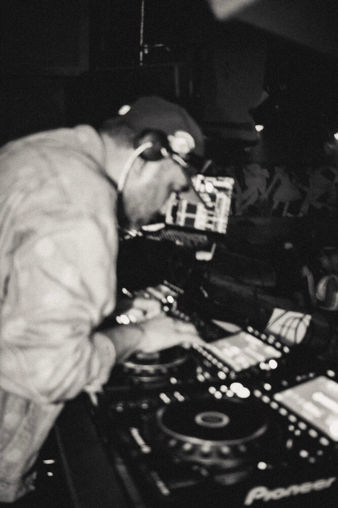 DJ operating turntables and mixing equipment at night