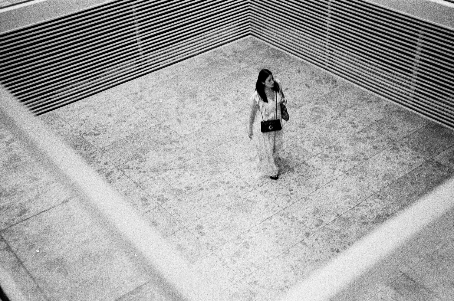 Woman standing alone in an empty concrete basin, shot from above in black and white