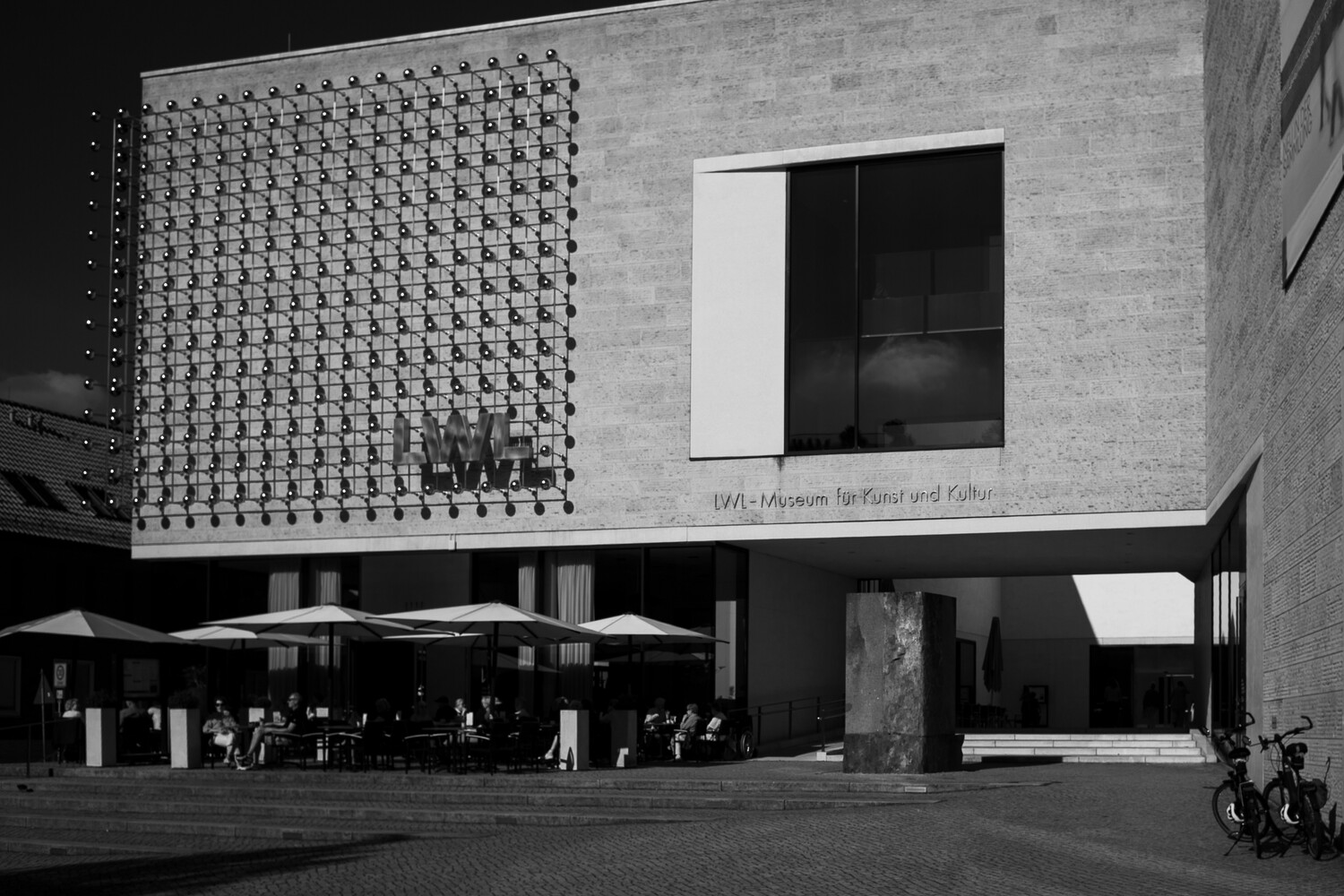 Modernist building facade with perforated metal panel and geometric window against brick wall