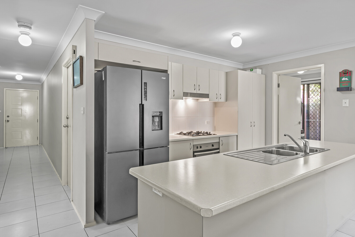 Modern kitchen interior with white cabinetry, stainless steel appliances, and white countertop island