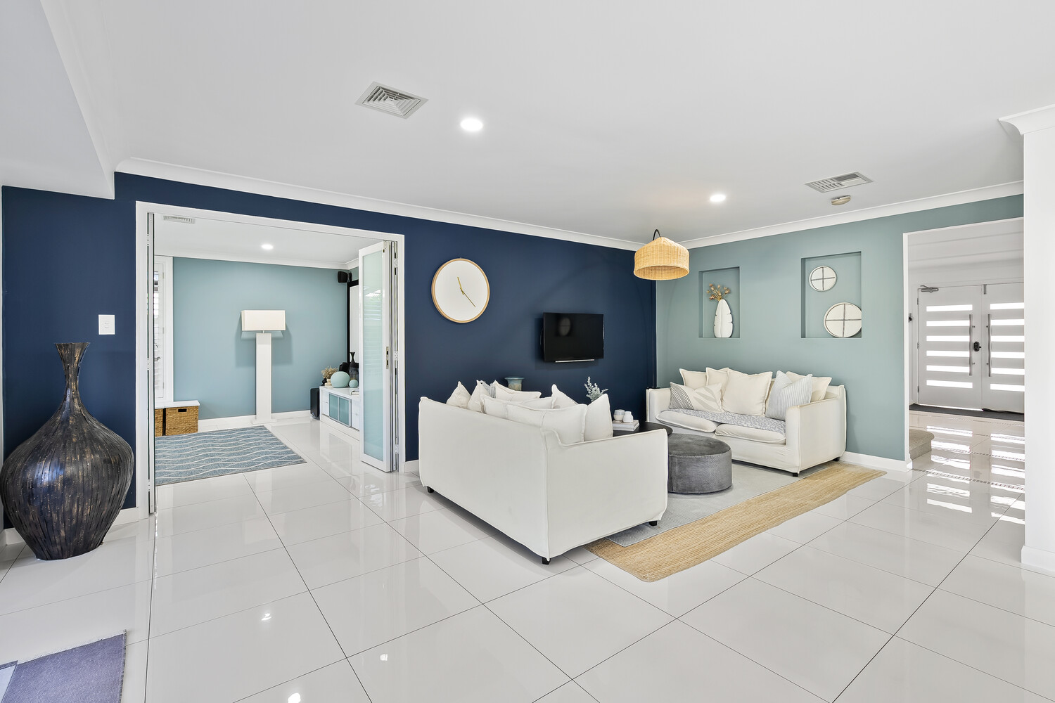 Luxury modern living room with navy blue and light blue accent walls, white sectional sofa, and polished tile flooring