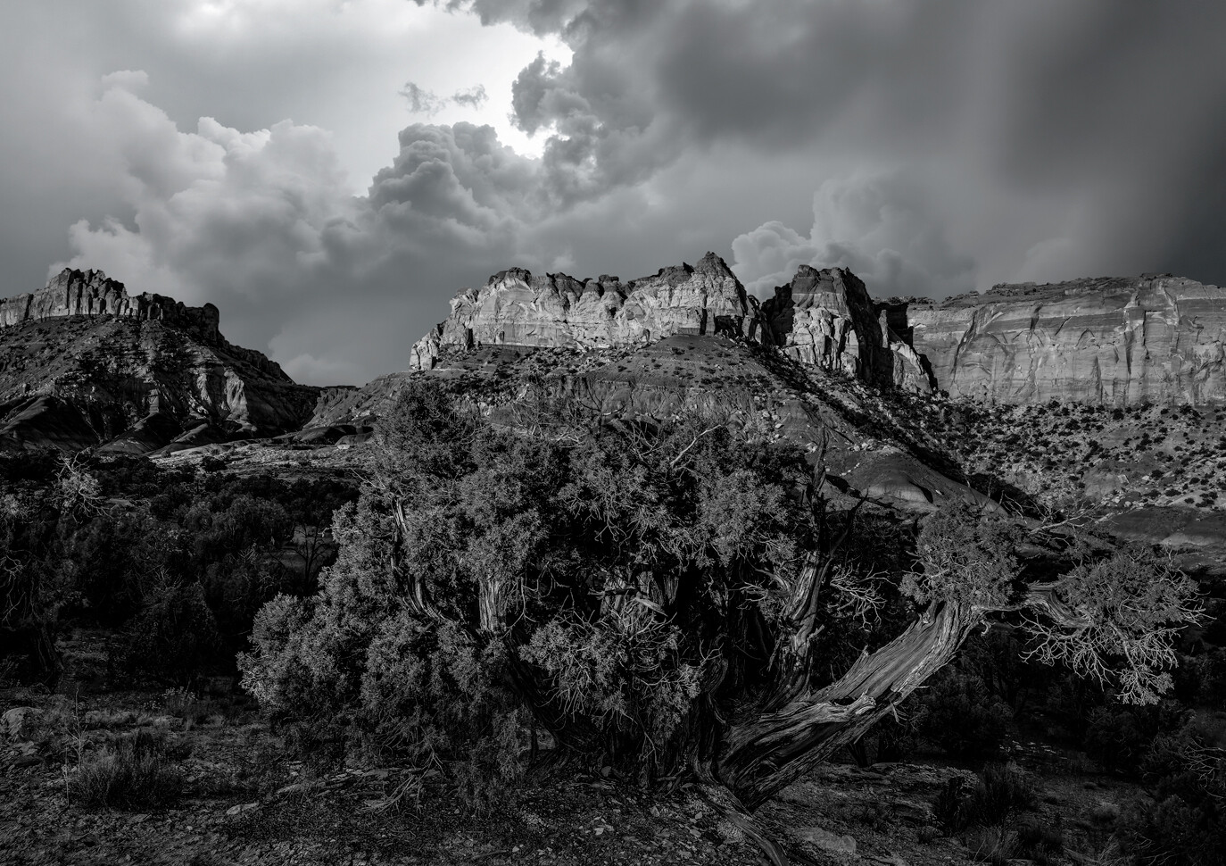 Dramatic black and white landscape of layered rock formations beneath stormy clouds