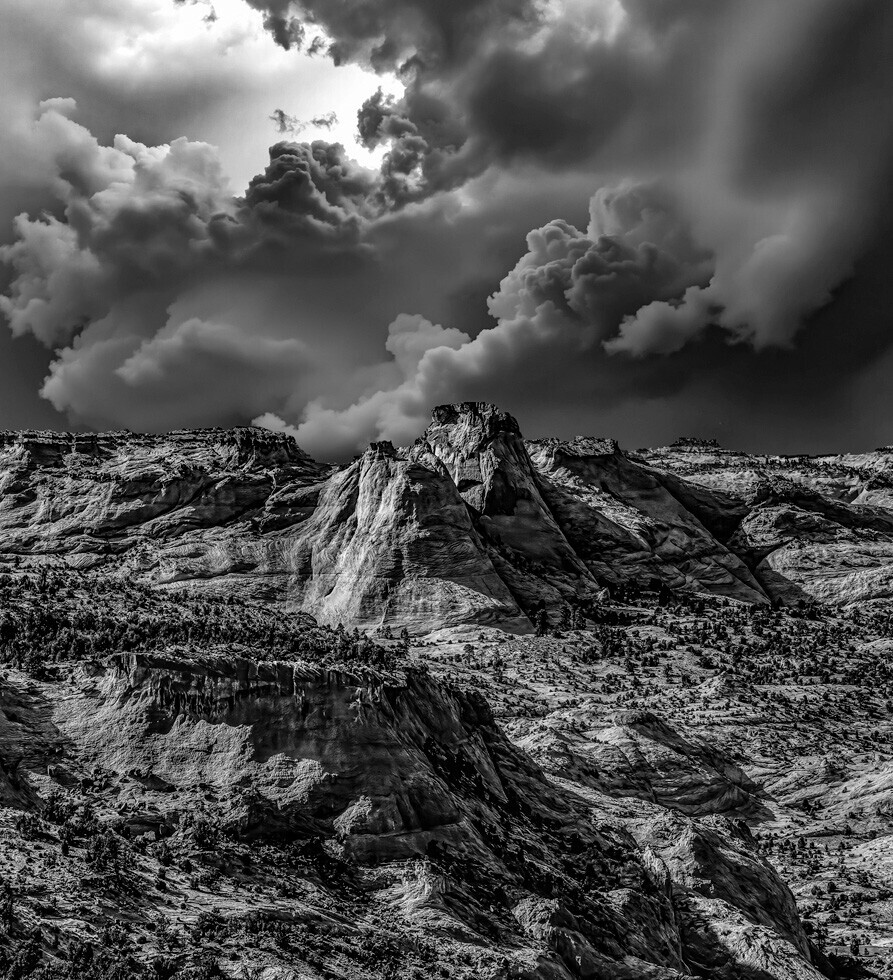 Dramatic black and white landscape with towering rock formations under turbulent storm clouds