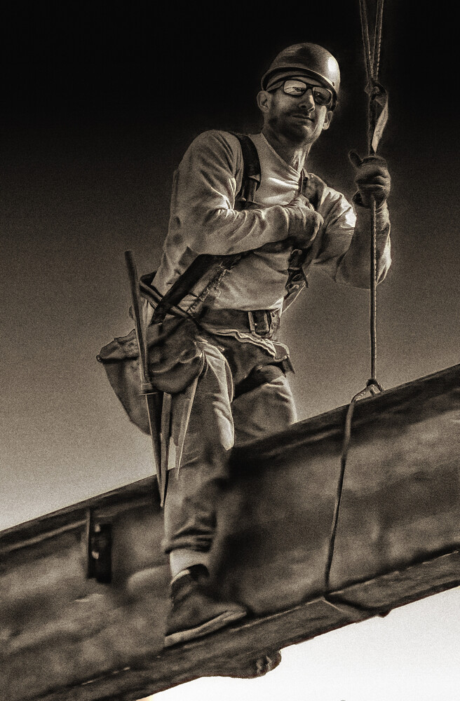 Worker in safety gear balanced on beam holding rope during construction or rigging work