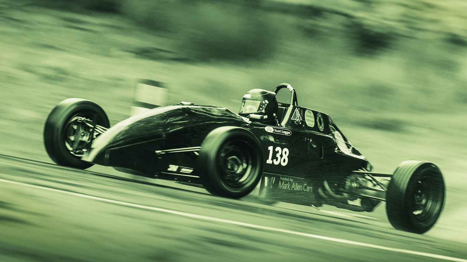 Black vintage race car number 138 in motion on a curved road with motion blur