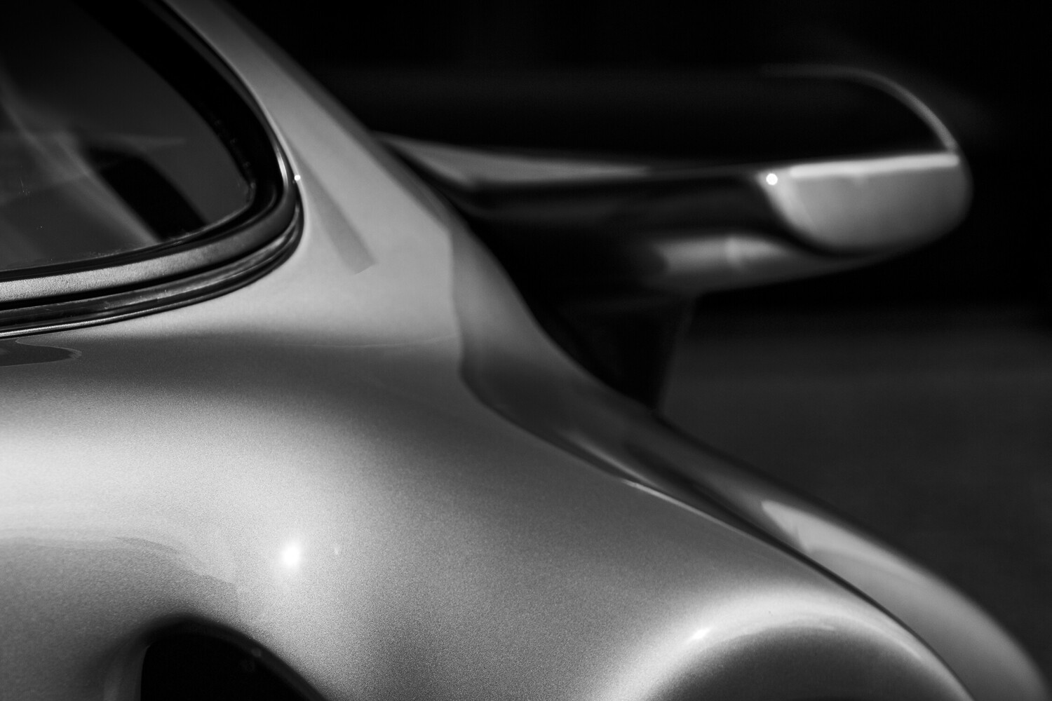 Close-up detail of a car's side panel and door handle in black and white