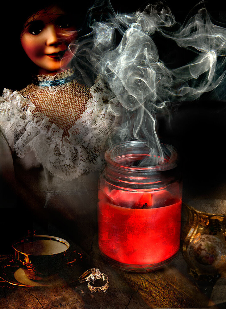 Antique porcelain doll with a lace collar beside a glowing red jar releasing swirling smoke on a dark wooden table