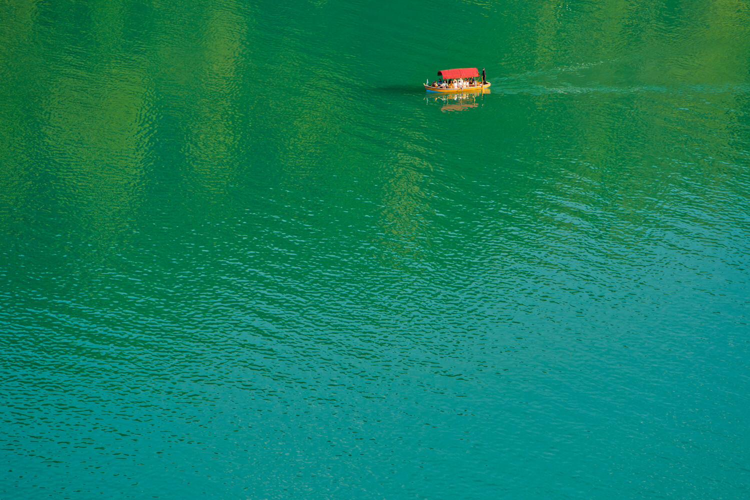 Red and yellow boat floating on turquoise water viewed from above