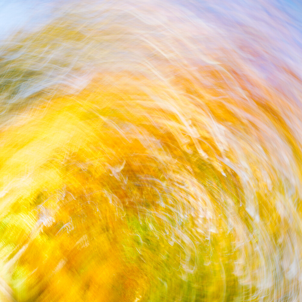 Abstract motion blur with swirling yellow, green, and white tones radiating outward