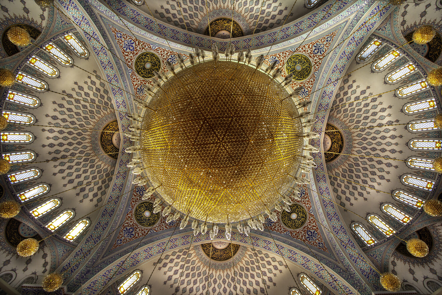 Symmetrical overhead view of an ornate domed ceiling with golden center and geometric Islamic patterns