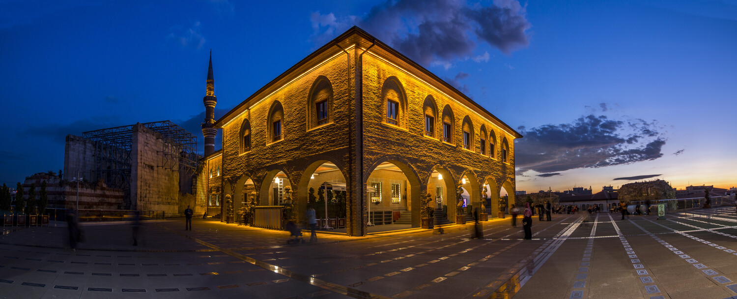 Illuminated historic stone building with arched windows at twilight in a public square