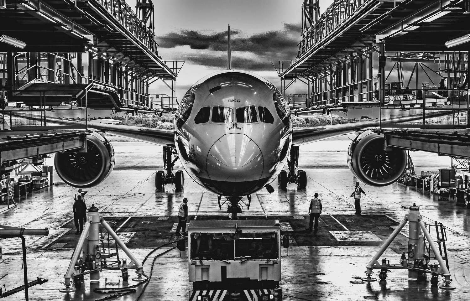 Commercial aircraft on airport tarmac shot symmetrically between two hangar structures in black and white