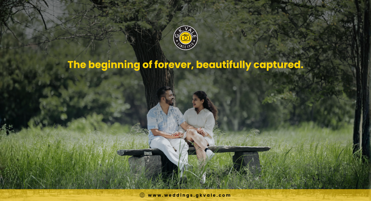 Couple sitting on a bench under a large tree in a grassy field, holding hands