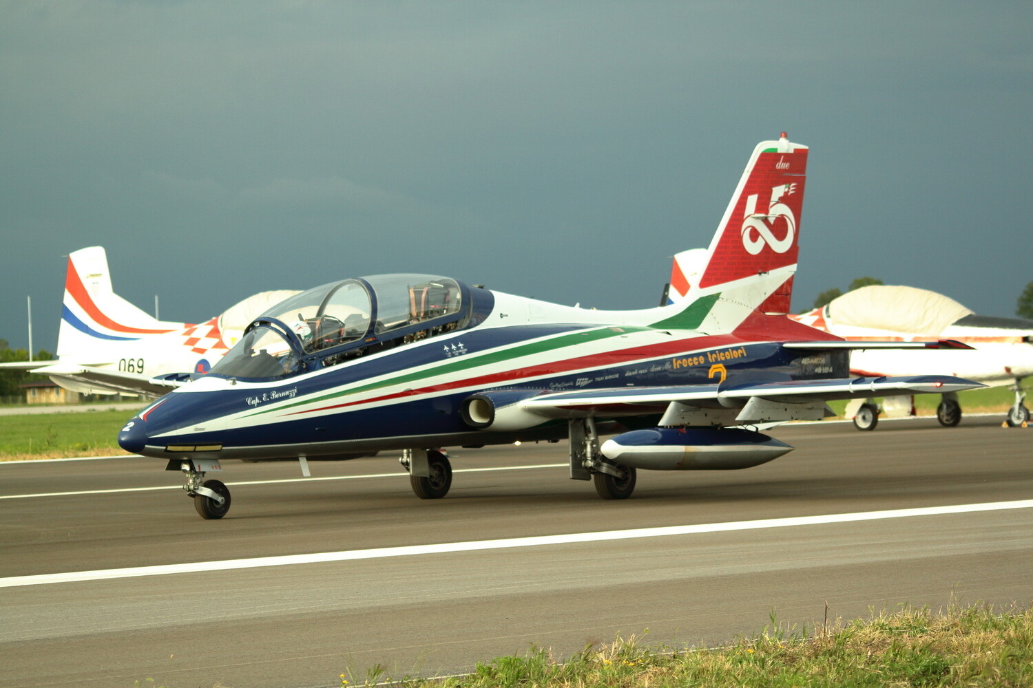 Red and blue aerobatic aircraft with distinctive paint scheme on runway