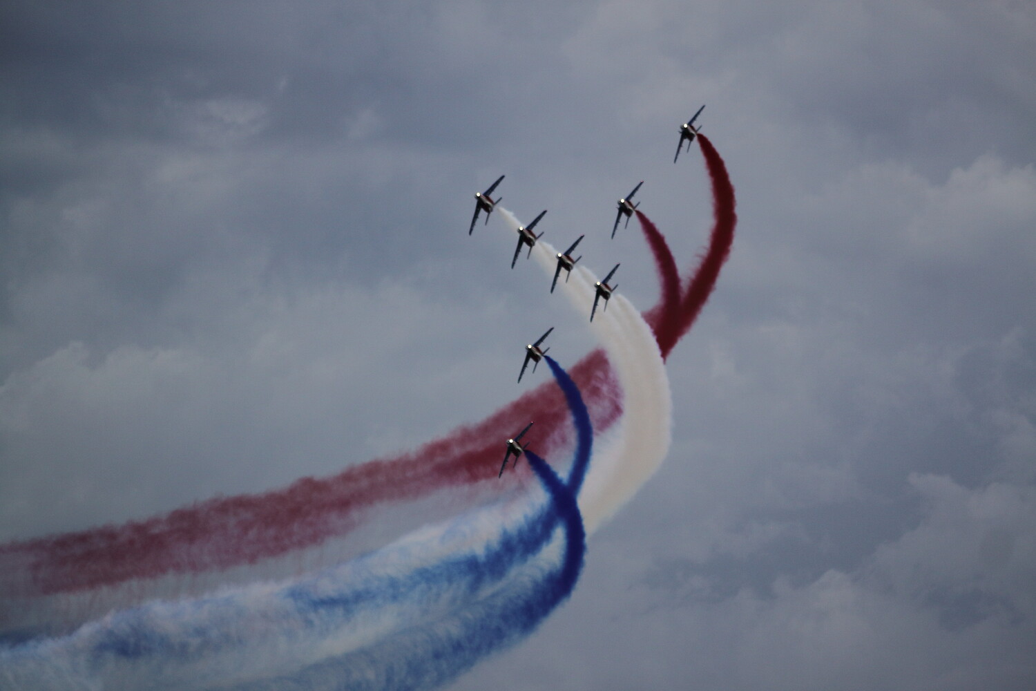 Military jets performing an aerial display with red, white, and blue smoke trails