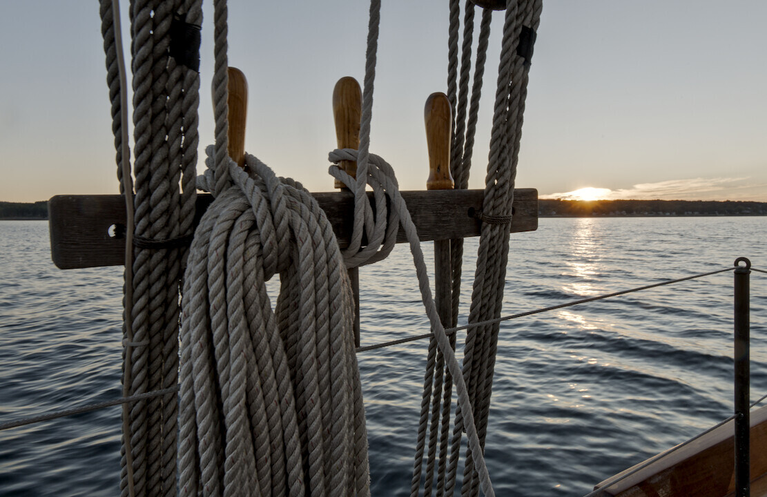 Coiled rope and wooden pulleys on a sailing vessel at sunset