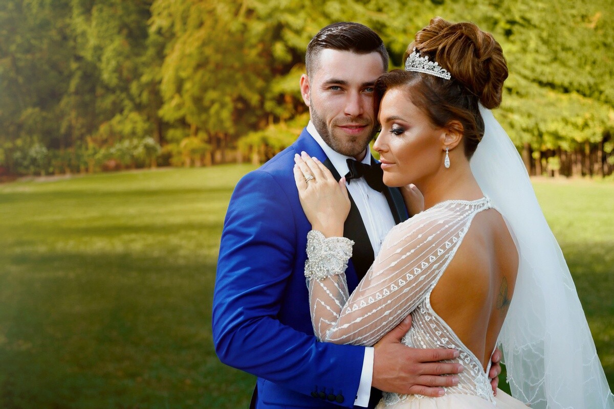 Bride and groom posing together outdoors with green landscape background