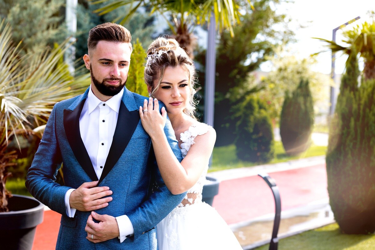 Bride and groom posing together outdoors in formal wedding attire