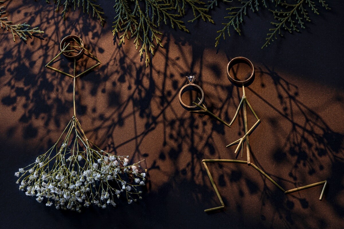 Dried baby's breath flower suspended with gold wire rings casting shadows on dark background
