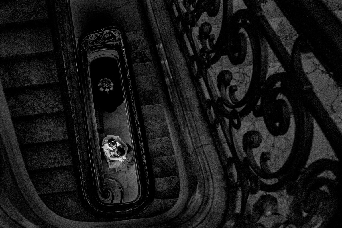 Overhead view of spiral staircase with ornate iron railings in black and white