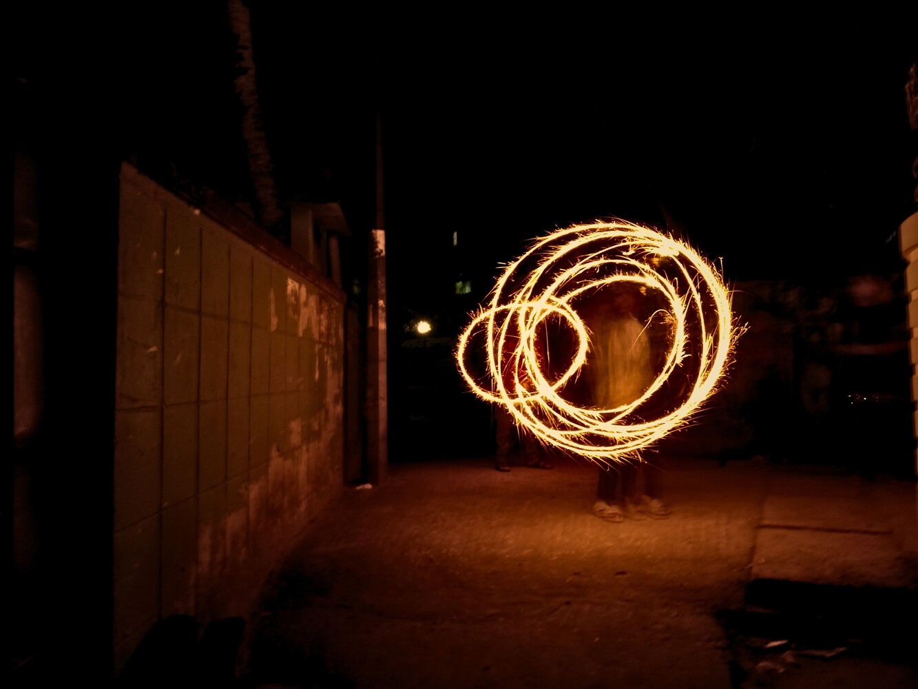 Glowing circular light painting spiral against dark urban alley at night