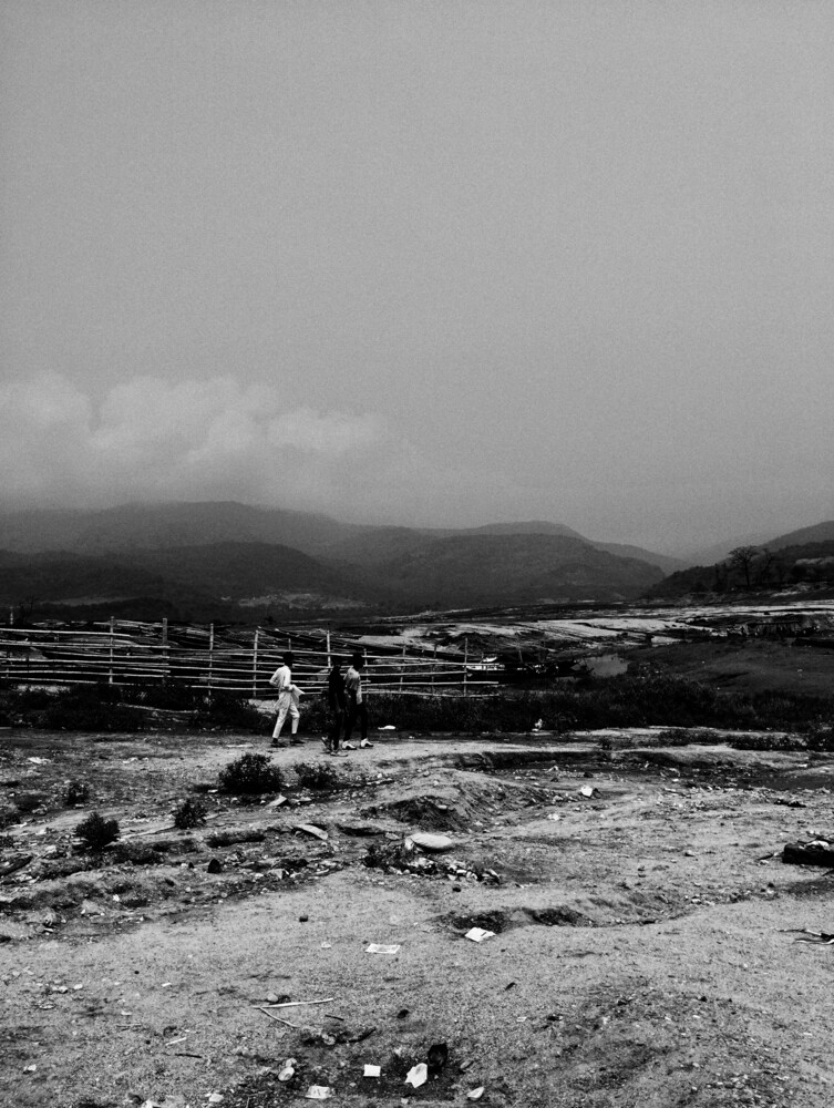 Solitary figure standing on rocky beach with mountains and overcast sky